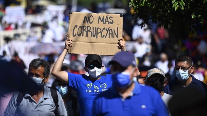Un hombre sostiene un cartel que dice "No m&aacute;s corrupci&oacute;n" durante una protesta contra el presidente Nayib Bukele y por un poder judicial independiente, 12 de diciembre de 2021.