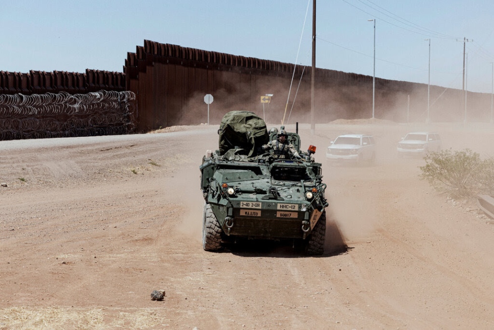 Un soldado conduciendo un veh&iacute;culo de combate Stryker junto al muro fronterizo.